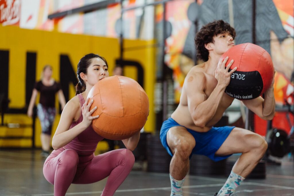 Asian couple working out with medicine balls, showcasing dynamic strength and fitness.